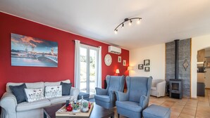 Een woonkamer met een rode muur, een bank, twee fauteuils, een salontafel en een open haard.