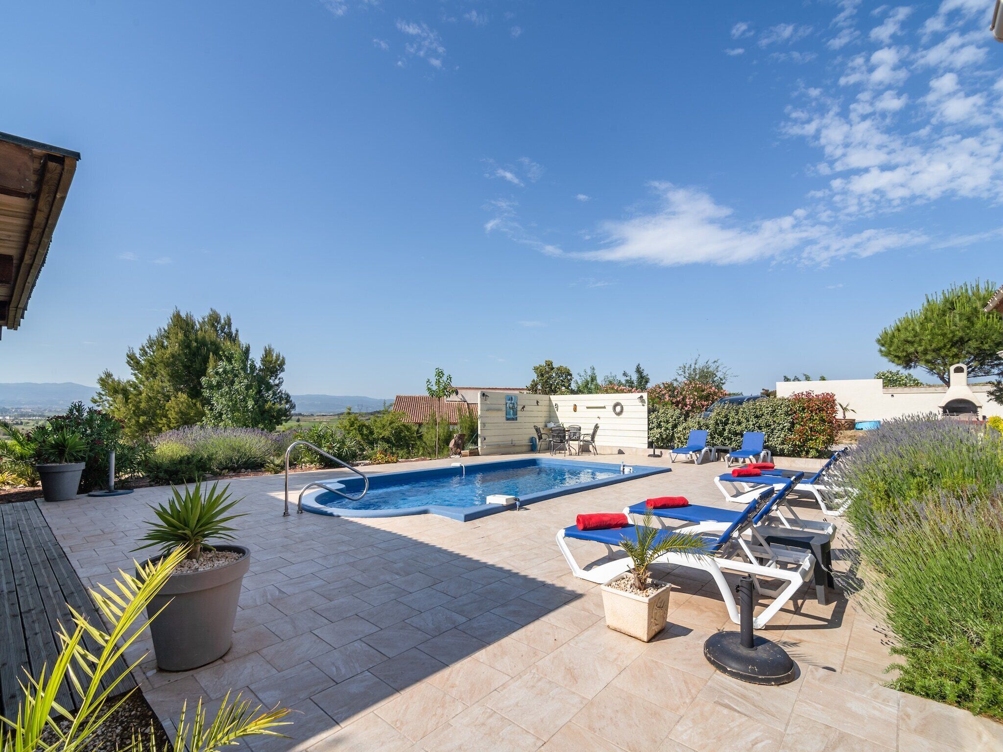 A rooftop pool area with lounge chairs, a small pool, and potted plants.