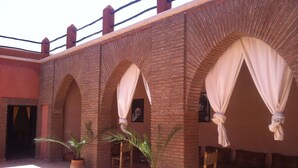 Un patio con arcos de ladrillo, plantas en macetas y una zona de estar con cojines.