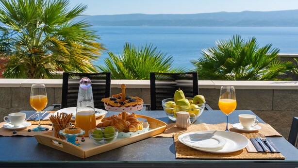 A breakfast table with croissants, fruit, and juice, overlooking a scenic view of the sea and mountains. - Villa Allegra with 32msq heated pool, 300m far from sandy beaches, open sea view (Duce)