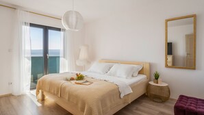 A bedroom with a bed, a small round side table, a mirror, and a view of the outdoors. - Villa Allegra with 32msq heated pool, 300m far from sandy beaches, open sea view (Duce)