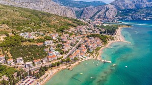 An aerial view of a coastal town with a beach, clear turquoise waters, and mountainous backdrop. - Villa Allegra with 32msq heated pool, 300m far from sandy beaches, open sea view (Duce)