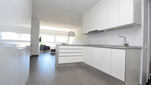 Una cocina moderna con armarios blancos, encimera de granito y horno integrado.