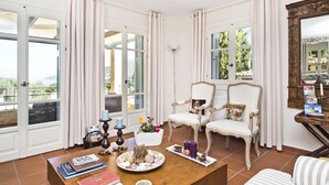 A room with a wooden coffee table, two white chairs, a large mirror, and a view of the outdoors through large windows. - 'Phivos Villa'Elegant Villa With Dramatic Mountain & Sea Views, Totally Equipped (Kefalonia)