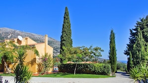 A Mediterranean-style building with a tiled roof, surrounded by lush greenery and a mountain backdrop. - 'Phivos Villa'Elegant Villa With Dramatic Mountain & Sea Views, Totally Equipped (Kefalonia)