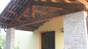 A wooden pergola structure with a brick wall and a door with shutters.