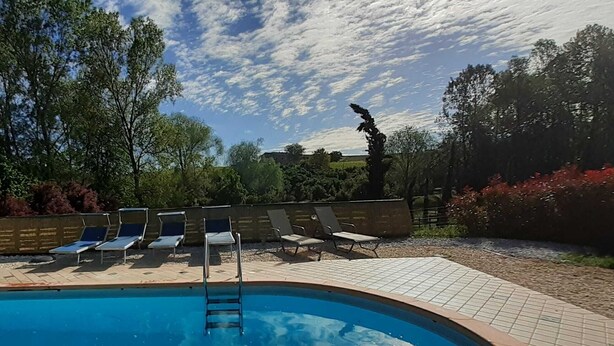 A swimming pool with lounge chairs and a ladder.
