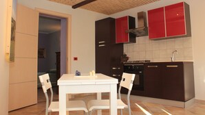 A modern kitchen with white cabinetry, a dining table with chairs, and a tiled backsplash.