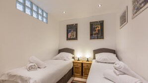 A bedroom with two single beds, a nightstand with lamps, and posters on the wall. - Le Pied du Brevent -  a studio that sleeps 4 guests (Chamonix)