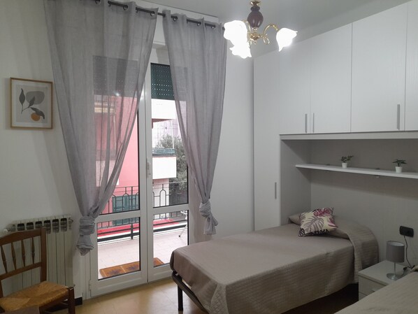 A bedroom with a bed, a chair, a radiator, a window with curtains, a ceiling light, and a view of the outside balcony. - Very central apartment Sestri Levante CIN IT010059C2BLDX7B62 (Sestri Levante)