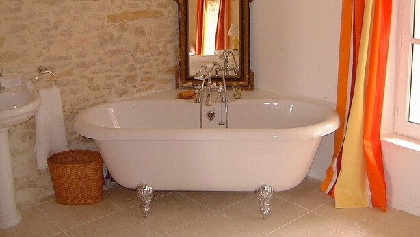 Ein Badezimmer mit freistehender Badewanne, Waschbecken und Spiegel.