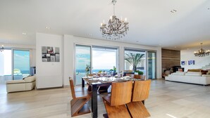 A spacious living room with a dining area, large windows, and a view of the ocean. - Bay View Villa Cyprus, Luxury at its finest!! (Protaras)