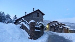 Kivinen rakennus, jonka sisäänkäynti on lumen peitossa, ja taivas on kirkas.