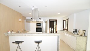 A modern kitchen with a central island, stainless steel appliances, and pendant lighting. - Villa with pool and BBQ. Air conditioner. Table tennis. Wi-Fi. 15 minutes (Palma de Mallorca)