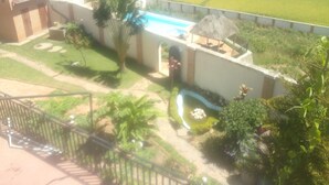 Zona residencial con piscina, una construcción de techo de paja y césped bien cuidado.