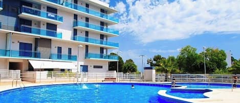 Un edificio moderno con varios balcones y una piscina grande.