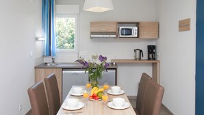 Eine moderne Küche mit Mikrowelle, Kaffeemaschine und einer kleinen Essecke mit Tisch für zwei Personen.