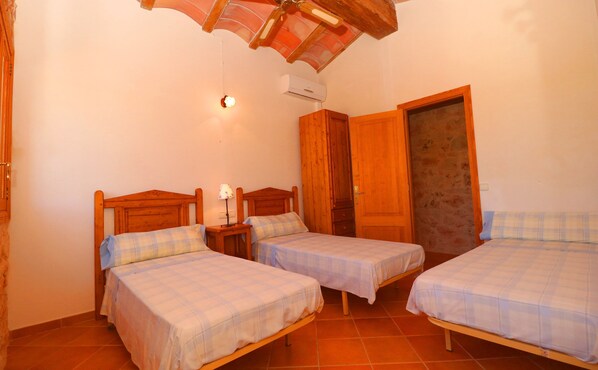 A room with three wooden beds, each with a matching headboard and footboard, and a nightstand with a lamp between the beds. - Can Guillem, Air Conditioning, Wifi free, private pool, Garden (Campos)
