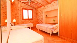 Un dormitorio con dos camas individuales, un armario de madera, un estante pequeño con una planta y una ventana con cortinas.