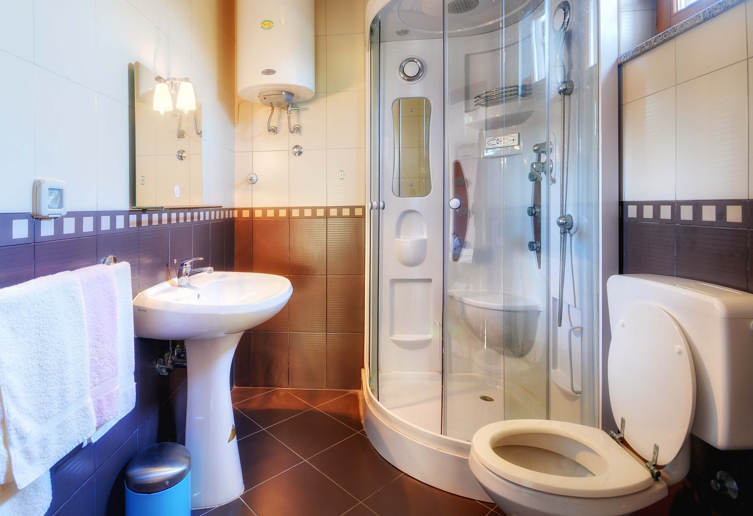 A bathroom with a sink, toilet, and glass-enclosed shower stall.