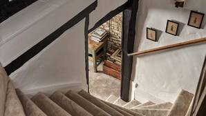 A staircase with a beige carpet, white walls with black trim, and a wooden bench with books. - Cotswolds home in Castle Combe (optional Hot Tub) (Castle Combe)