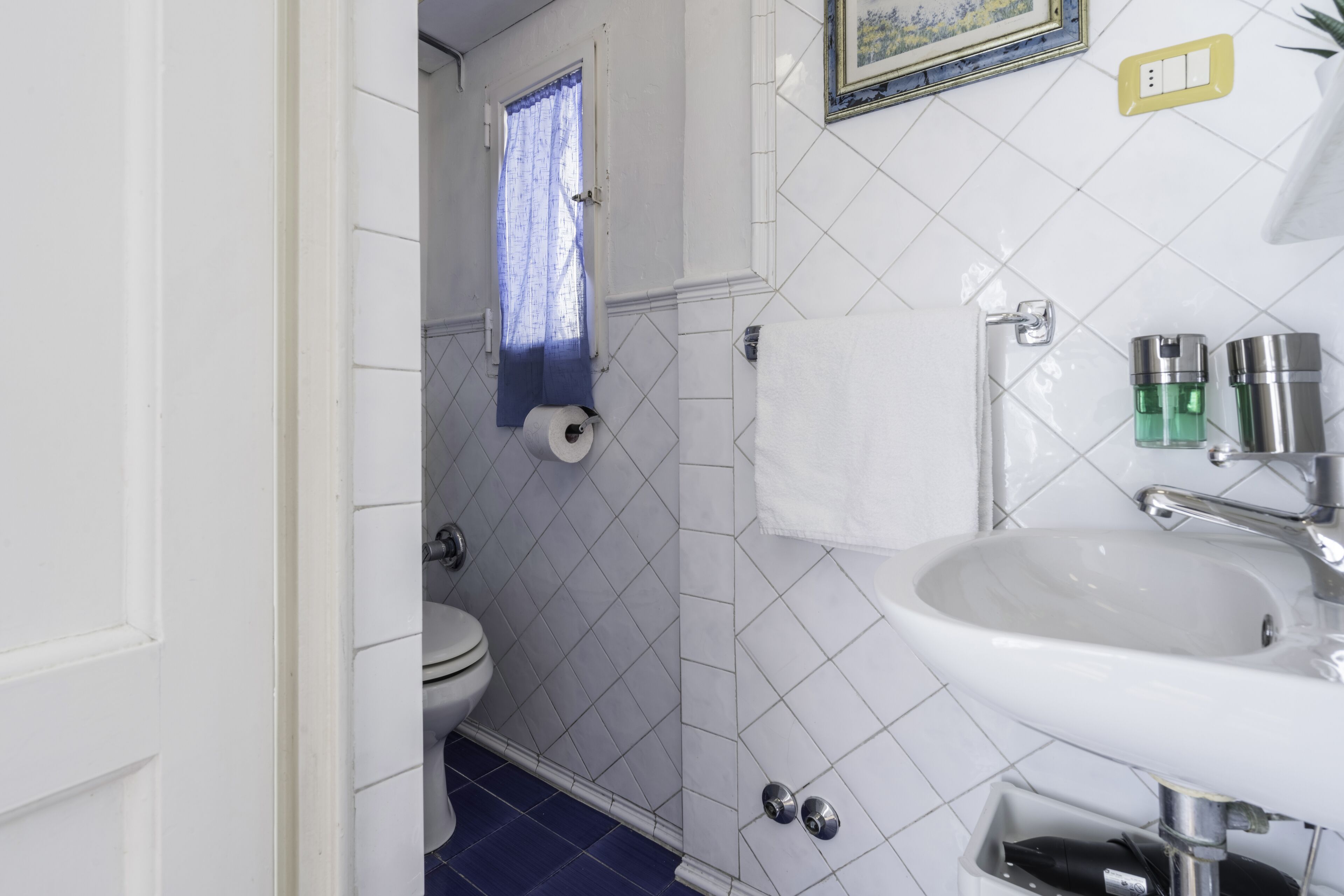 A bathroom with a white sink, toilet, and blue-tiled floor.