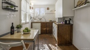 Uma cozinha compacta com uma mesa de madeira, uma máquina de lavar roupa e uma garrafa de vinho.