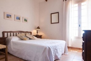 A bedroom with a bed, a nightstand, a lamp, and three framed pictures on the wall.