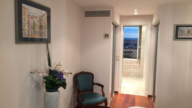 Ein Hotelzimmer mit Bett, Sessel, Blumen in einer Vase und einem Bild an der Wand.