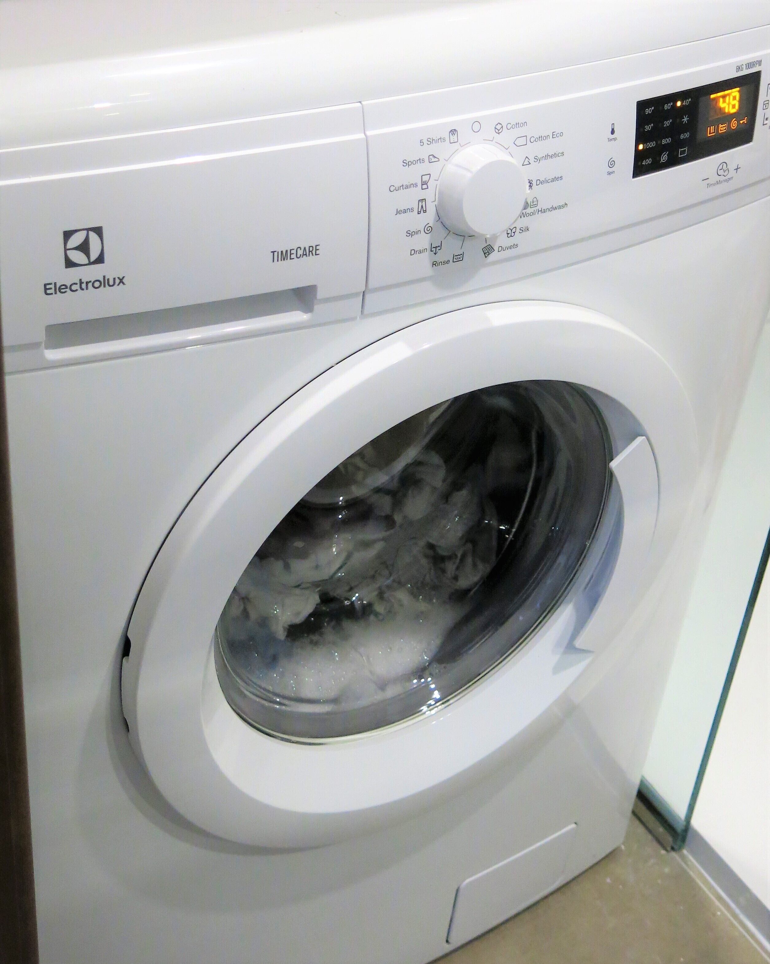 Valkoisen Electrolux-pesukoneen etupuoli, jossa on digitaalinen näyttö ja s äätönuppi.