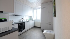 Eine moderne Küche mit weißen Schränken, einem eingebauten Backofen und einem Fenster für natürliches Licht.