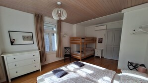 Ein Schlafzimmer mit Etagenbett, Schreibtisch, Stuhl, Kommode und einem Fenster mit Vorhängen.