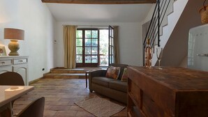 Una sala de estar acogedora con una mesa de madera, un sofá y un ventanal con cortinas.