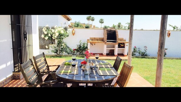 An outdoor patio with a round table, chairs, and a grill.