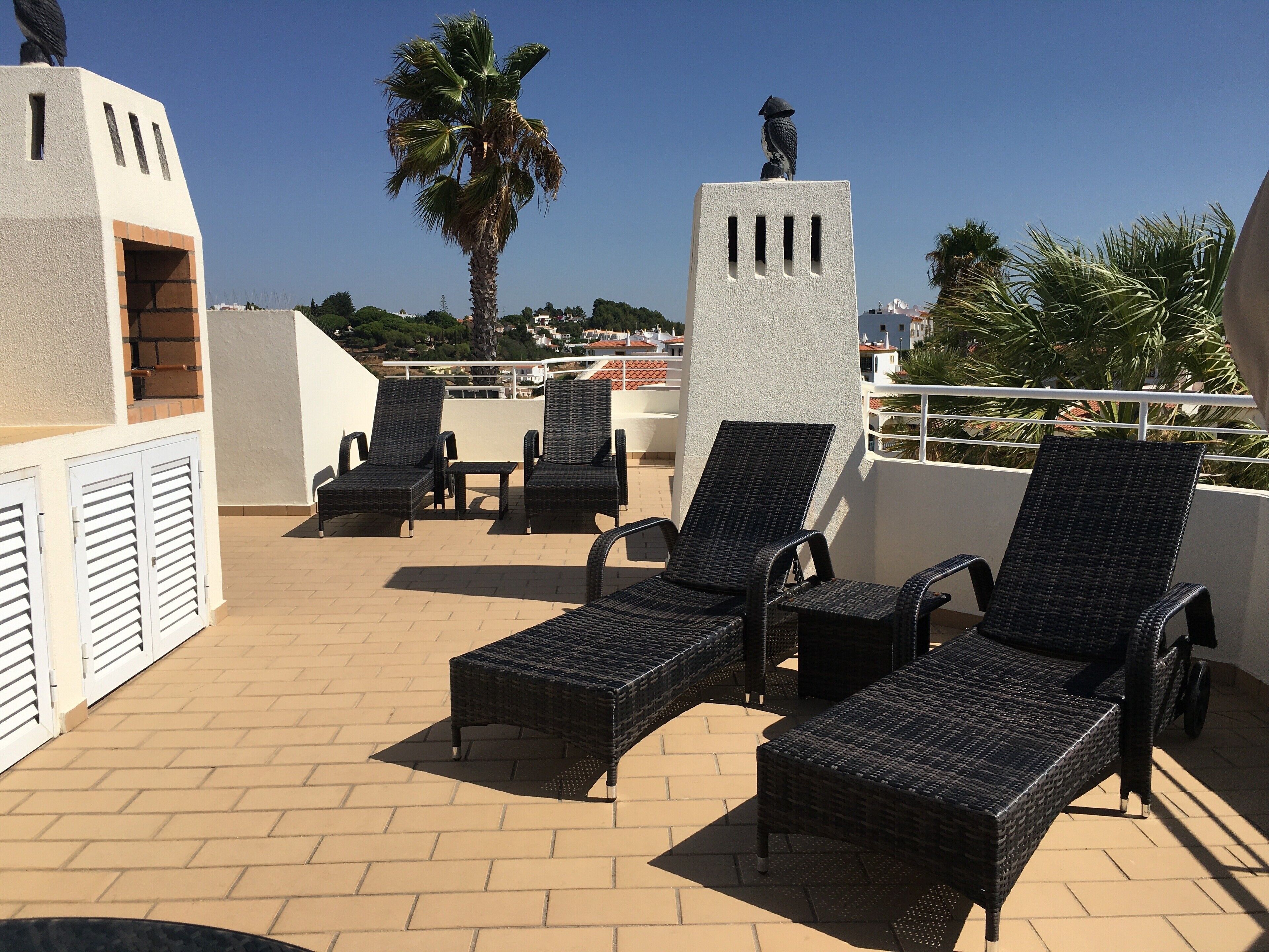 Una terraza en la azotea con sillones de mimbre, una estatua y vistas de la ciudad.