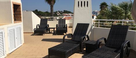 Una terraza en la azotea con sillones de mimbre, una estatua y vistas de la ciudad.