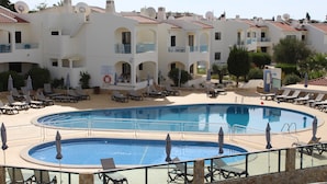 Un hôtel doté d’une grande piscine, de nombreux balcons et de chaises longues.