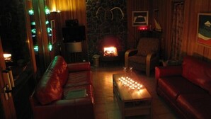 A cozy living room with a fireplace, leather sofas, and a coffee table with candles.