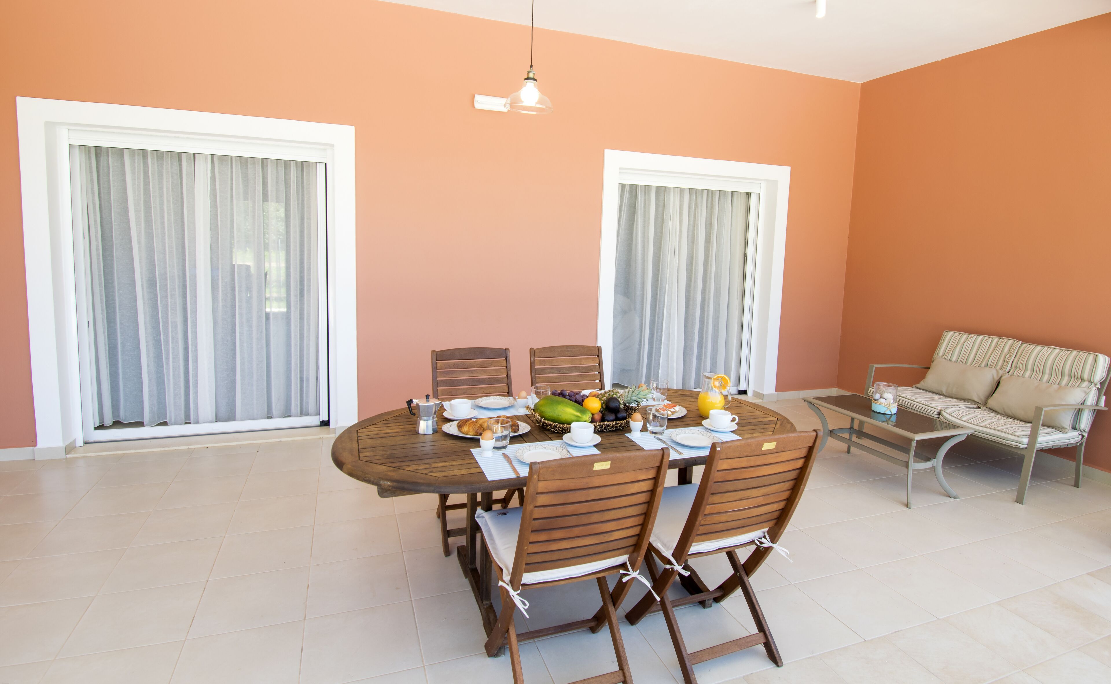 A dining area with a round table set for four, surrounded by wooden chairs.