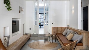 Una sala de estar moderna con un banco de madera, un tapete redondo y un televisor montado en la pared.