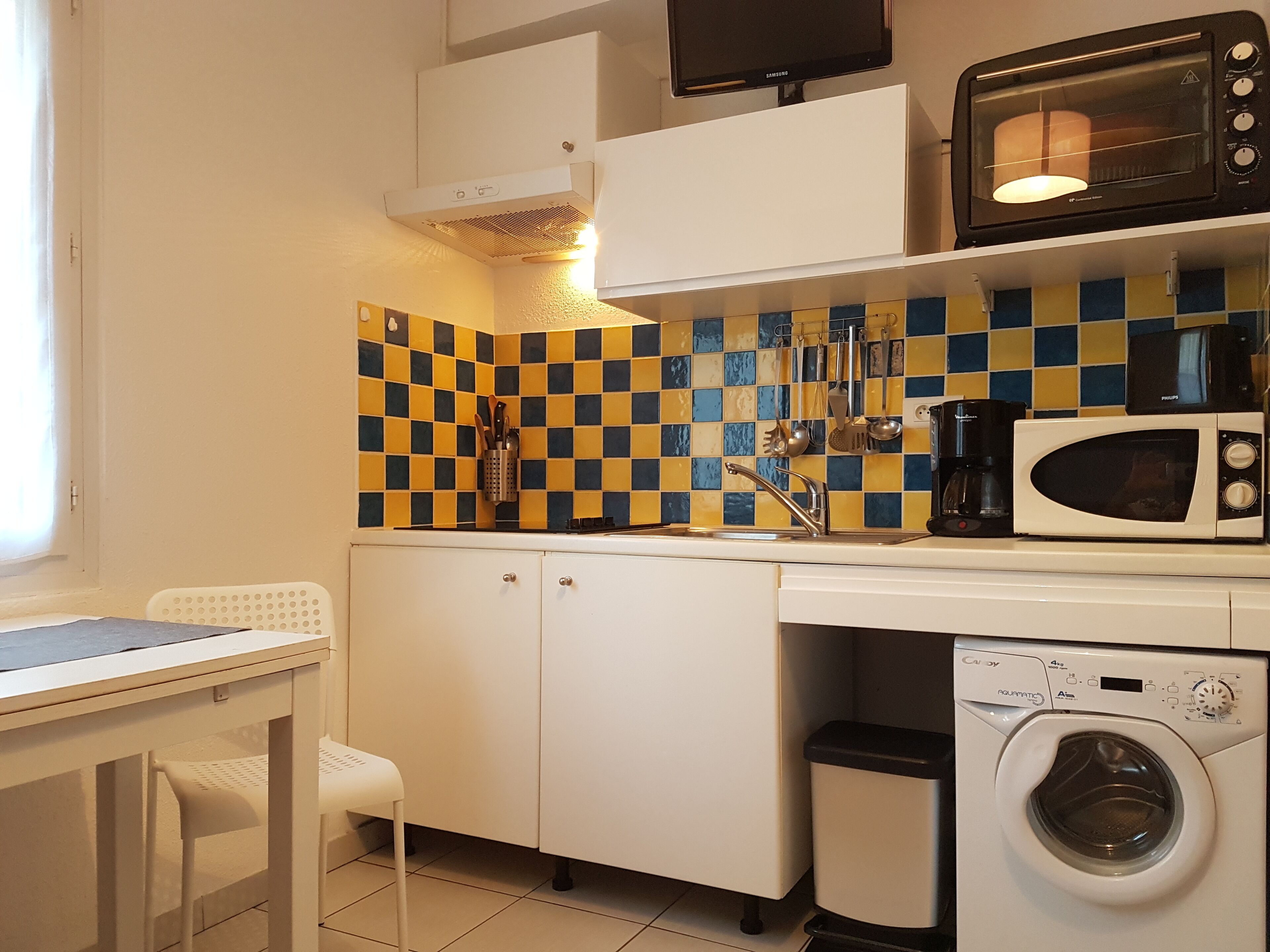 Cocina compacta con microondas, lavabo y lavadora.