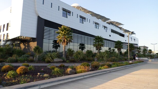 A modern building with a flat roof, large windows, and a reflective facade. - 1-room apartment for spa guests and vacationers (Balaruc-Les-Bains)