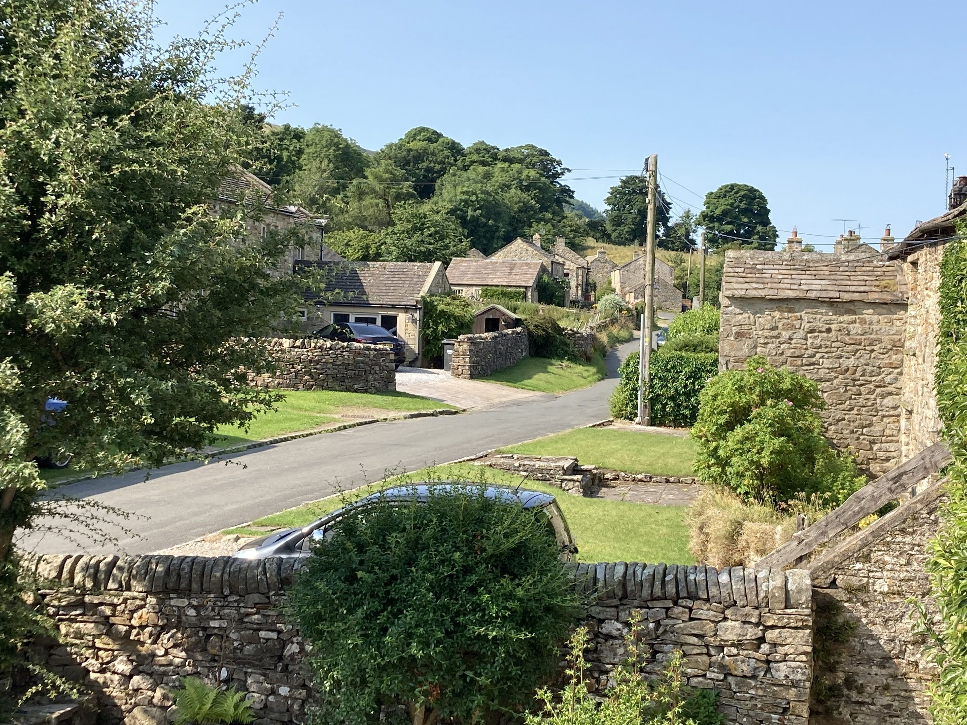 A rural street with stone walls and houses.