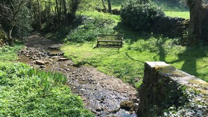 A stone wall with a bench in a lush green park. - Beautifully Converted Barn With Stunning Views near Aysgarth (Newbiggin Bishopdale)