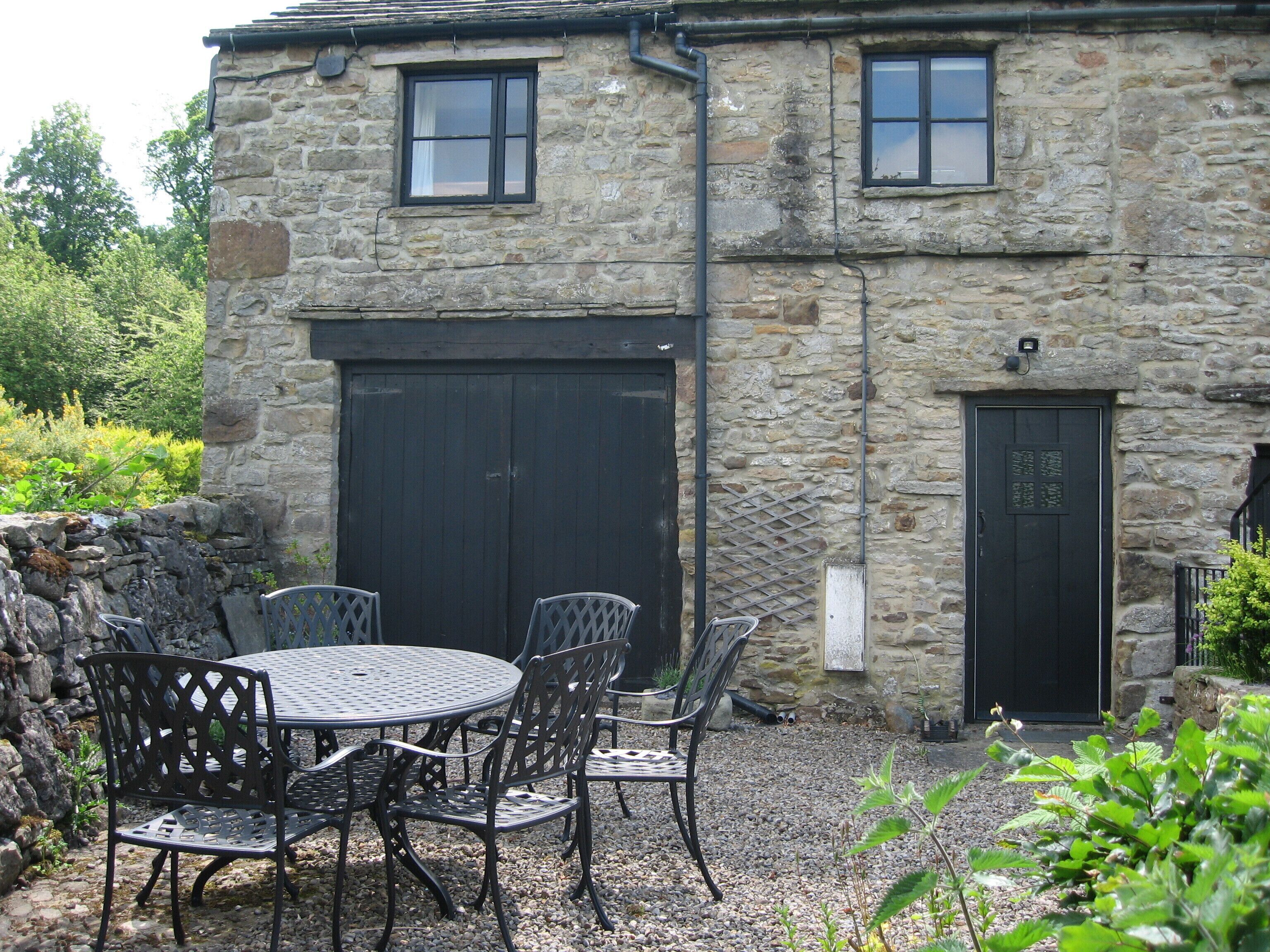 A stone building with a large garage door, a small door, and a window.