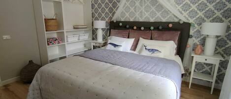 A bedroom with a bed, a wardrobe, a nightstand, and a patterned wallpaper.