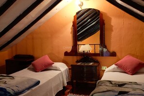 A room with two beds, a wooden dresser, a mirror, and a lamp.