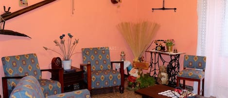 Una sala de estar acogedora con sillones estampados, una mesa de centro de madera y una máquina de coser.