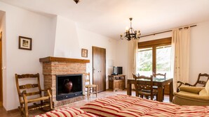 A cozy room with a fireplace, striped bedding, wooden furniture, and a television. - Accommodation with pool and paddle tennis court (Padul)
