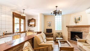 A spacious living room with a fireplace, a kitchen with a large window, and a cozy seating area. - Accommodation with pool and paddle tennis court (Padul)